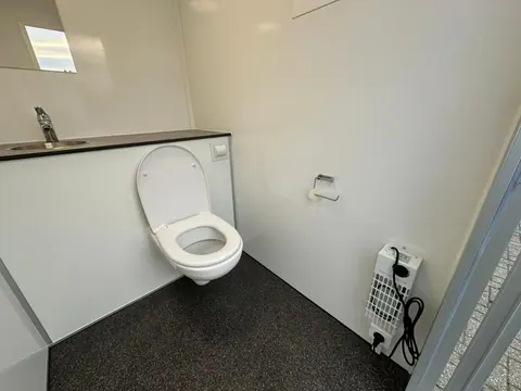 Toiletwagen 1+1, wandtoilet met een elektrische kachel ernaast