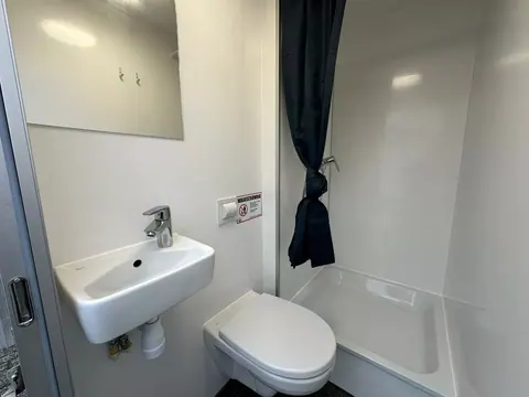 Dubbele mobiele badkamer, wastafel met kraan naast het wandtoilet en de douchebak