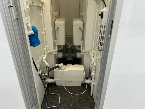 Dubbele mobiele badkamer, technische ruimte met de vermalers en de leidingen van beide badkamers