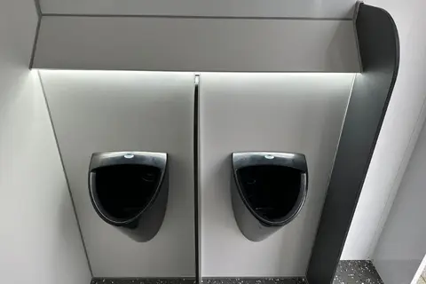 GL3200 1A212, twee donkere urinoirs tegen een grijze wand