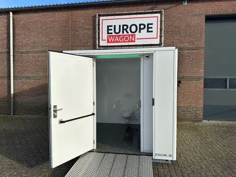 MIVA-toiletcontainer, met geopende deur bij een bedrijfsgebouw