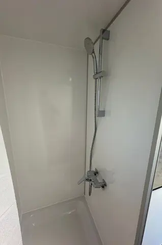 EW240, douche met een zilveren douchekop en gladde witte wanden