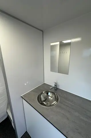 EW240, wastafel met een ronde metalen wasbak en een kleine spiegel erboven